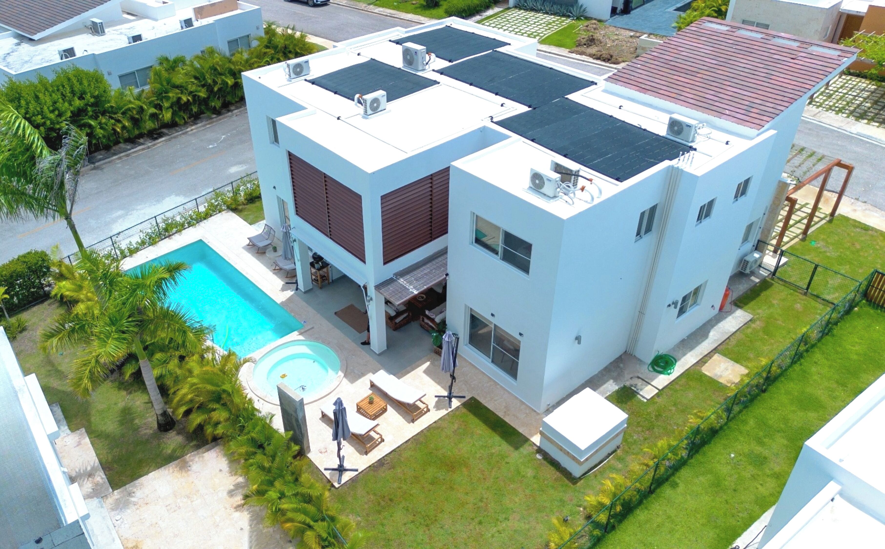 A modern building with a rooftop pool, a covered patio, and a well-maintained lawn.