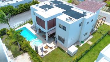 A modern building with a rooftop pool, a covered patio, and a well-maintained lawn.