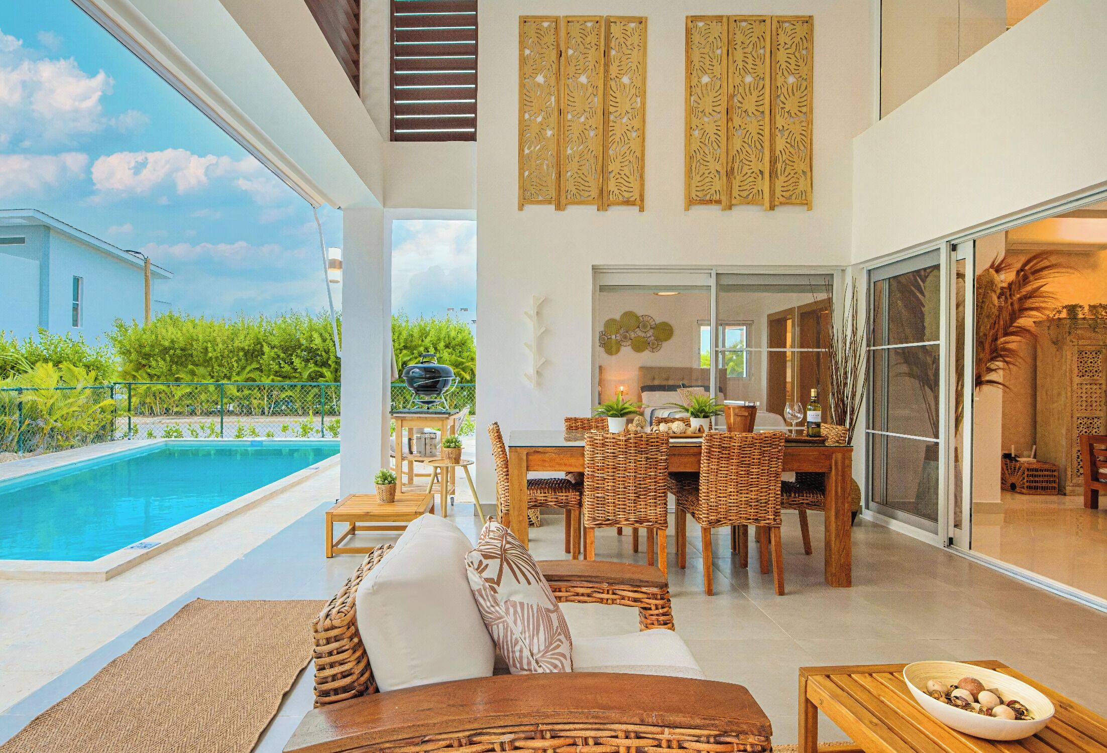 A spacious living area with a pool, dining set, and a sliding glass door leading to a balcony.
