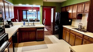 A kitchen with wooden cabinets, a central island, and a view to a dining area. - Large private home in gated horse farm in the heart of horse country! (Lexington)