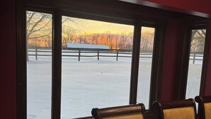 A dining area with large windows, wooden chairs, and a table set for dining. - Large private home in gated horse farm in the heart of horse country! (Lexington)