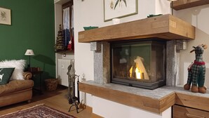 A cozy living room with a fireplace, a green wall, and a small Christmas tree.