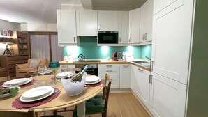 A modern kitchen with white cabinets, a microwave, and a dining area set for a meal.