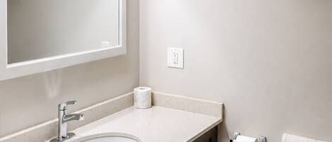 A modern bathroom with a sink, mirror, towel rack, and toilet.