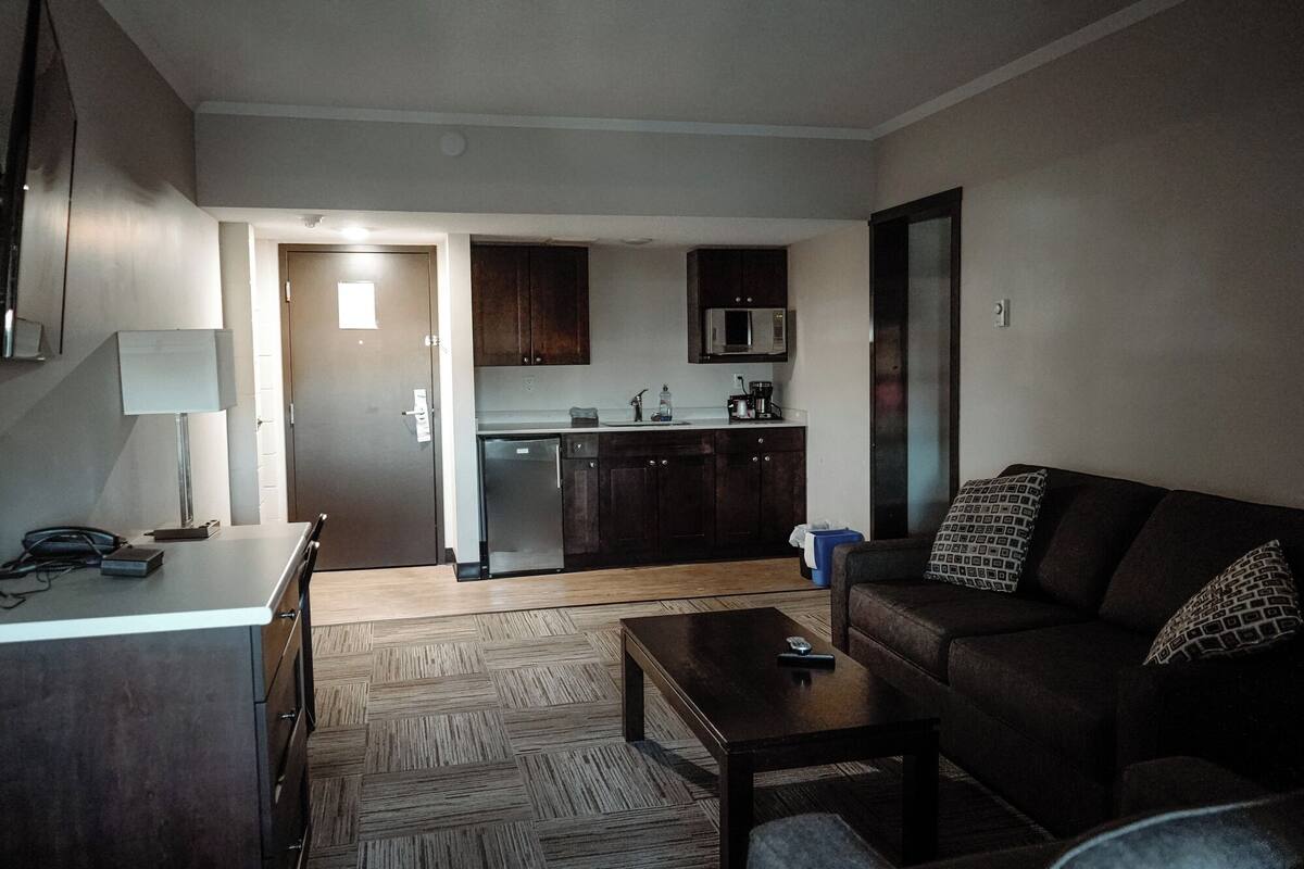 Un espacio habitable compacto con kitchenette, un sofá, una mesa de centro y una lámpara.