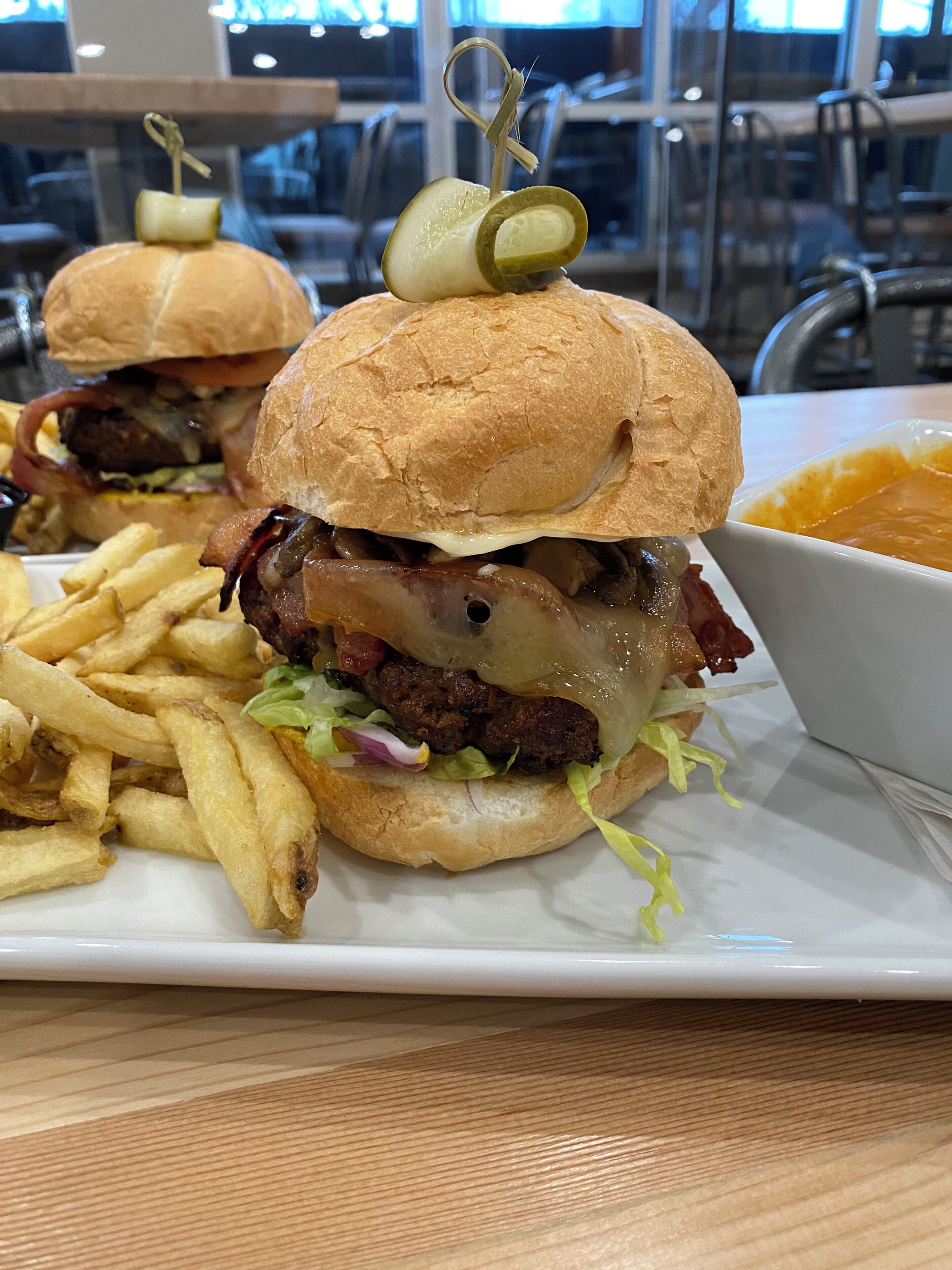 A meal consisting of burgers, fries, and a bowl of soup on a white plate.