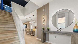 Un intérieur moderne avec un escalier en bois, un coin cuisine et un espace repas agrémenté de tabourets de bar.