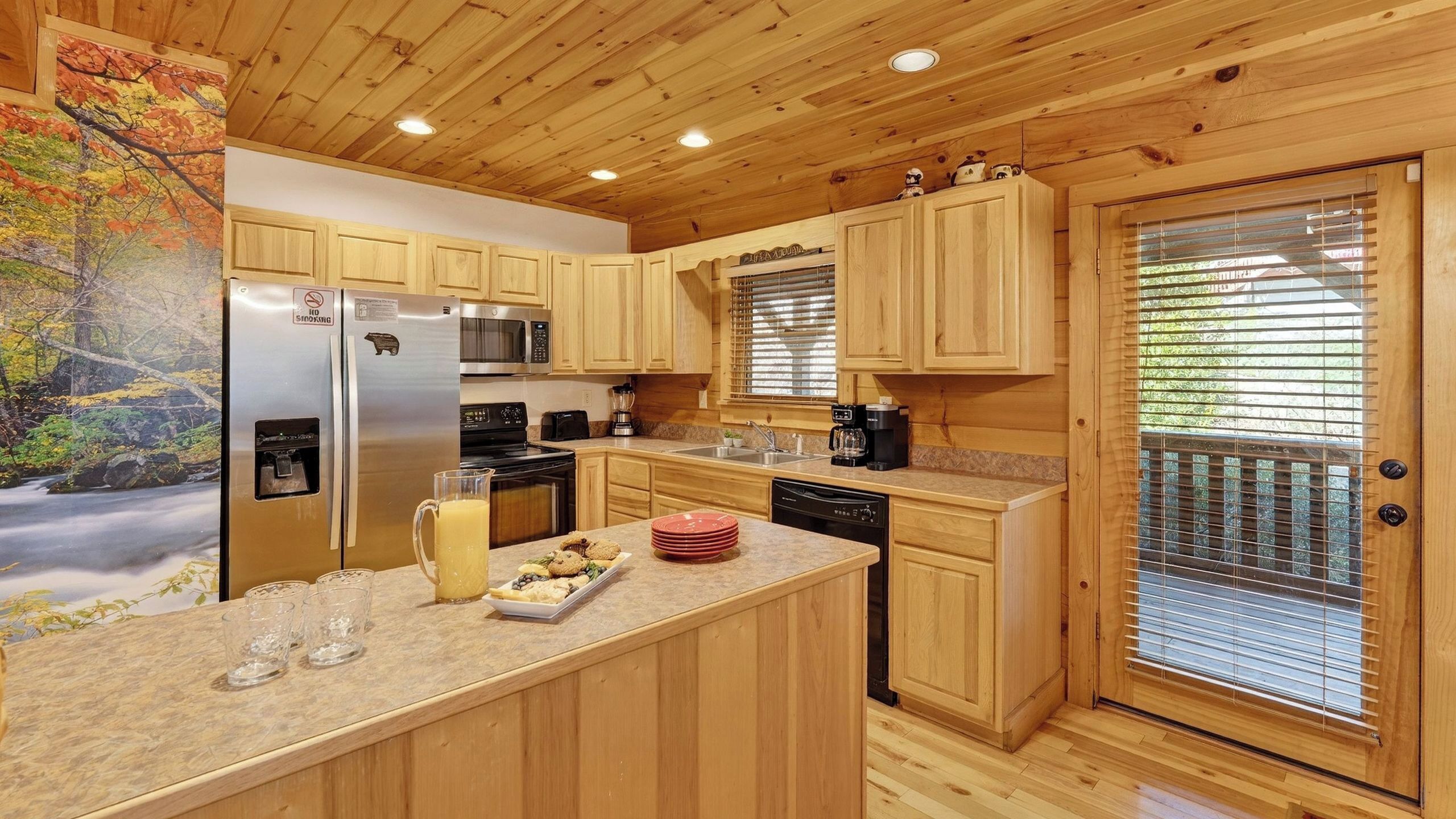 Una cocina tipo cabaña de madera con refrigerador, microondas, estufa y lavaplatos.