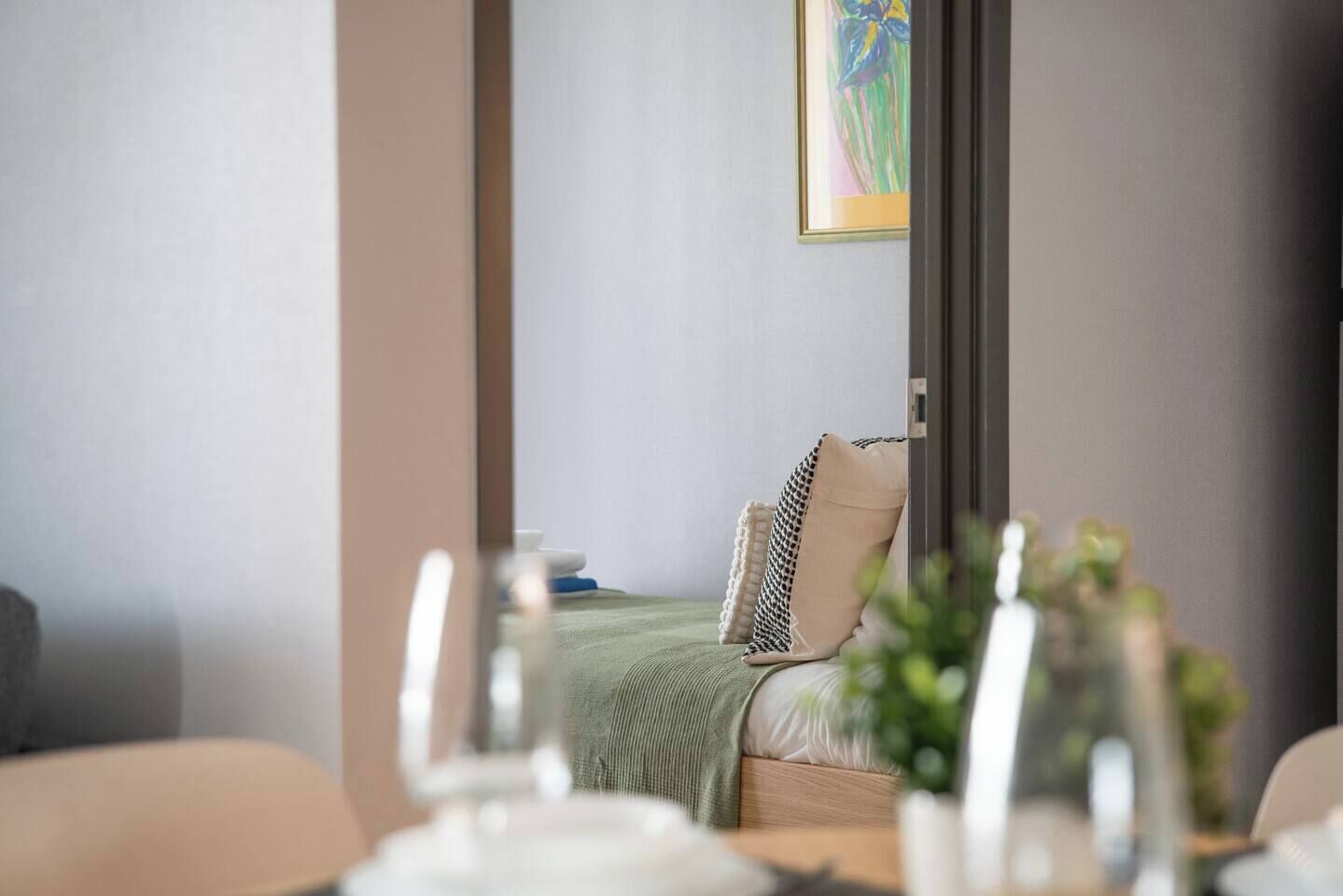 A hotel room with a bed, pillows, a bedside table, and a painting on the wall.
