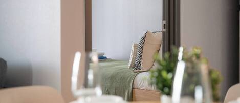 Quarto de hotel com cama, almofadas, mesa de cabeceira e um quadro na parede.