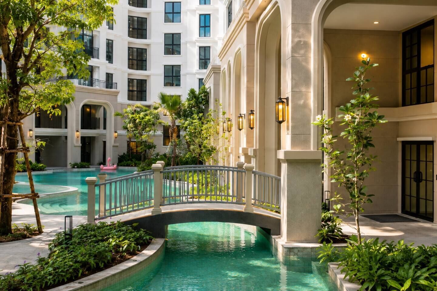 Ein HotelInnenhof mit Schwimmbad, einer Brücke und einem Gebäude mit mehreren Etagen und Balkonen.