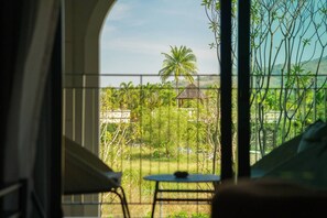 Ein Balkon mit Blick auf einen Garten, ein kleiner Tisch und ein Stuhl.