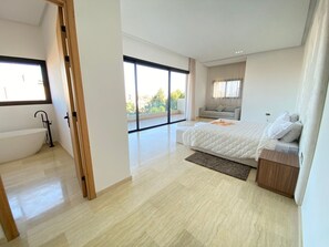 A modern bedroom with a large bed, a sofa, and a view of the outdoors. - Villa Prestige Piscine - Argan Golf gym (Marrakech)