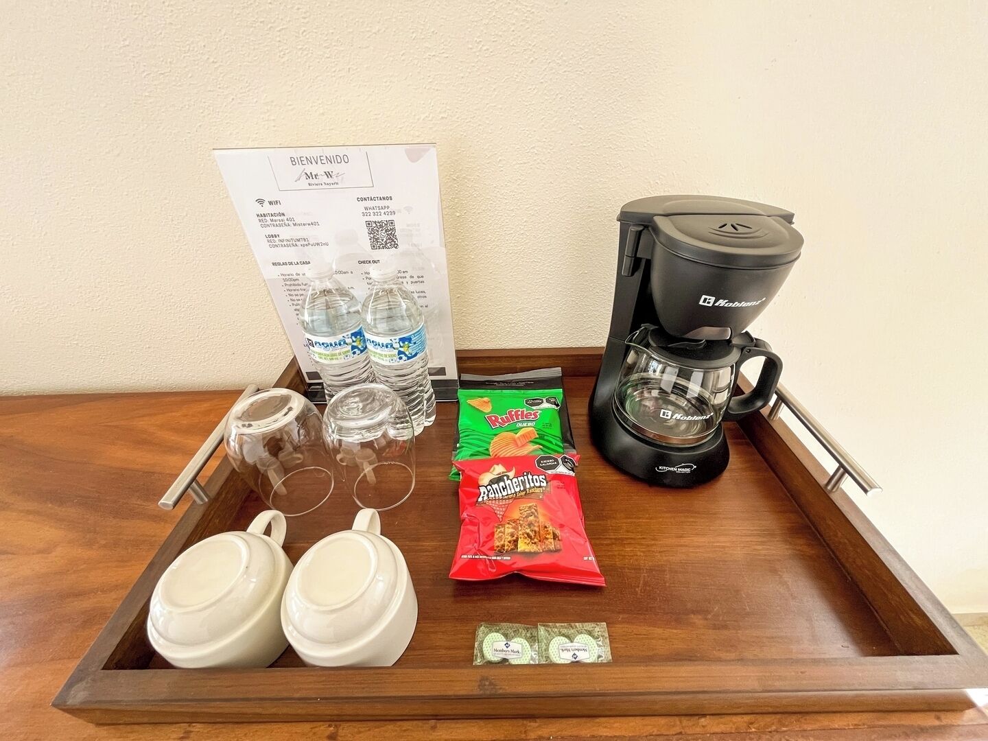 Un plateau avec une cafetière, des verres, des bouteilles d’eau et des en-cas.
