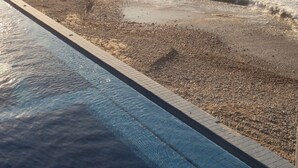 A beach with a swimming pool and a view of the ocean and distant land. - Mr. W | Sophisticated Apartment in Torre Marsai (Punta Negra)