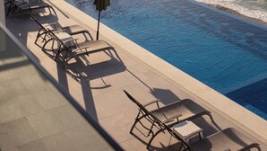 A poolside area with a view of the ocean, a small pool, and lounge chairs. - Mr. W | Sophisticated Apartment in Torre Marsai (Punta Negra)