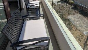 Ein Balkon mit Gartenmöbeln, freier Blick auf das Meer und ein Sandstrand.