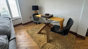 Un comedor con una mesa de vidrio, sillas negras, un tapete amarillo y una lámpara.