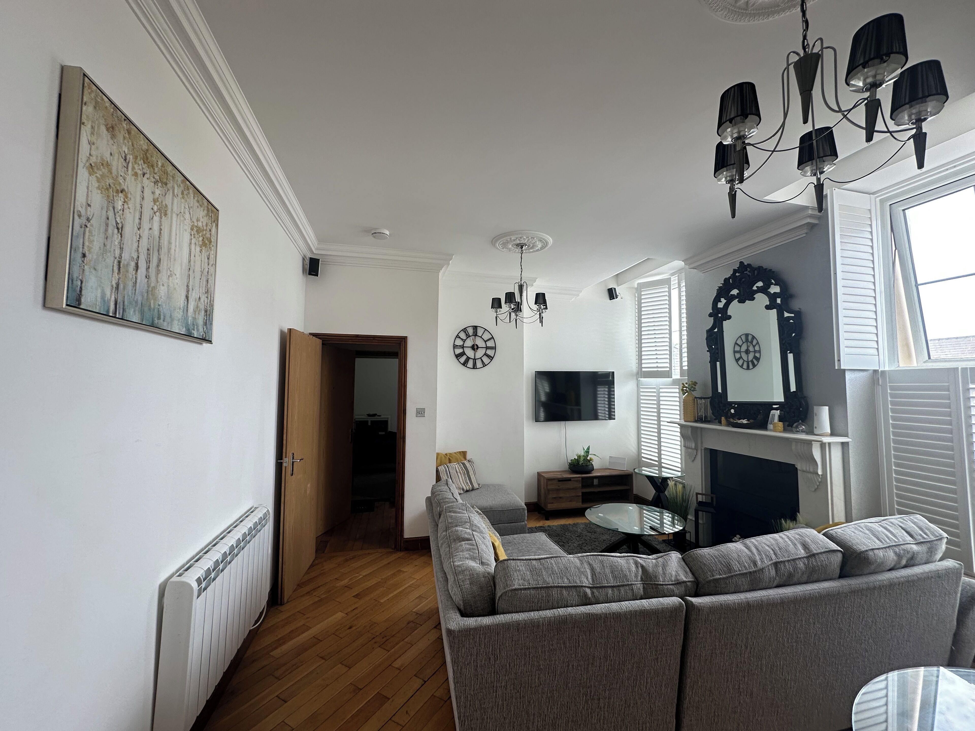 Una sala de estar moderna con un sofá seccional gris, una mesa de centro de vidrio, una chimenea y un televisor montado.