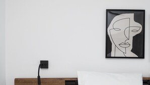 A modern bedroom with a wooden headboard, a black nightstand with a drawer, a white pillow, and a framed abstract artwork on the wall. - Exotic Villa, Private Pool with Lagoon Views – Romantic Escape in Halkidiki (Nea Moudania)