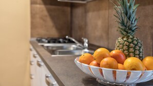 A kitchen with a stainless steel sink, a bowl of oranges, and a pineapple. - Sweet Dream Apartment 15 min to Venice · Bus 24/7 (Venezia)
