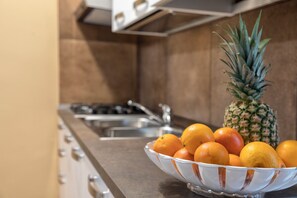Eine Küche mit einem Edelstahlspülbecken, einer Schüssel mit Orangen und einer Ananas.
