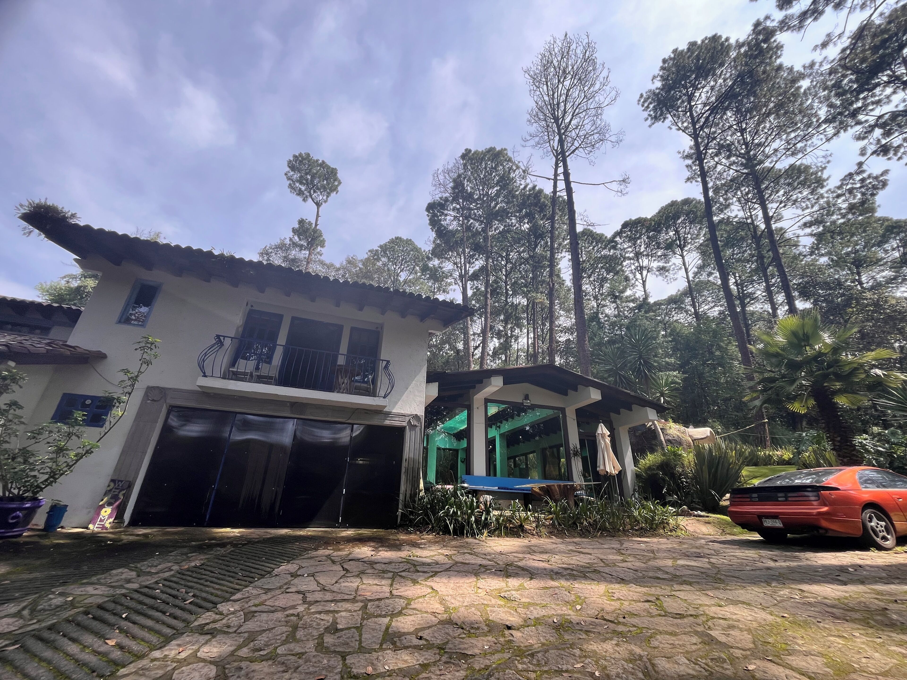 A two-story house with a garage, surrounded by trees and a parked car.