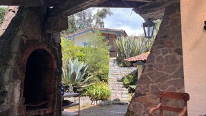 A rustic outdoor area with a brick oven, a wooden chair, and a stone wall. - Cozy 4-bedroom cabin in perfect harmony in Rancho ojo de luz cabañas de aventura (Rancho Avándaro Country Club)