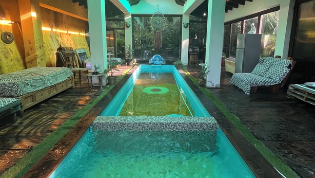 A pool area with a central water feature, seating on either side, and a view of the outdoors. - Cozy 4-bedroom cabin in perfect harmony in Rancho ojo de luz cabañas de aventura (Rancho Avándaro Country Club)