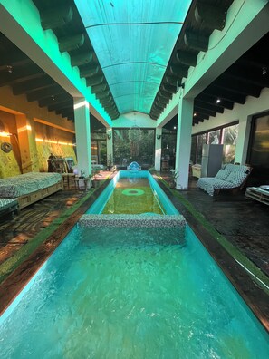 A pool area with a central water feature, seating on either side, and a view of the outdoors. - Cozy 4-bedroom cabin in perfect harmony in Rancho ojo de luz cabañas de aventura (Rancho Avándaro Country Club)