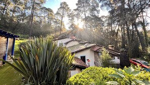 A house with a tiled roof, surrounded by dense trees and greenery. - Cozy 4-bedroom cabin in perfect harmony in Rancho ojo de luz cabañas de aventura (Rancho Avándaro Country Club)