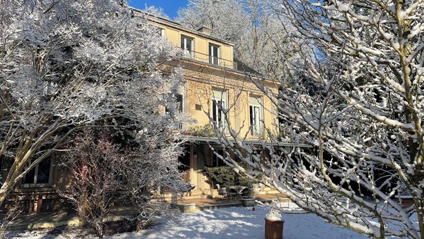 A building with a balcony, surrounded by snow-covered trees.