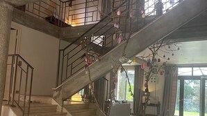 A spacious interior with a large staircase, a high ceiling, and a view of the outdoors.