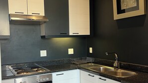 A modern kitchen with stainless steel appliances, white cabinetry, a built-in oven, a microwave, a sink, and a washing machine. - Peaceful 1-bedroom apartment in charming Cape Town- The View on Long (Cape Town)