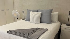 A modern bedroom with a large bed, a bedside table, a nightstand, and a wall-mounted fan. - Peaceful 1-bedroom apartment in charming Cape Town- The View on Long (Cape Town)