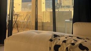 A room with a bed, a window with a view of the cityscape, and a balcony with a chair and table. - Peaceful 1-bedroom apartment in charming Cape Town- The View on Long (Cape Town)