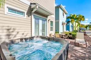 Ein Whirlpool vor einem Haus mit Terrasse und einem Stuhl.