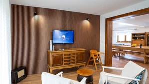 Ein Wohnzimmer mit Fernseher, Holzmöbeln und einem Essbereich.