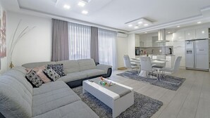 Un salon moderne comprenant un canapé, une table basse et un coin repas avec des chaises.