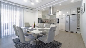 Une cuisine moderne dotée d’un îlot central, d’appareils électroménagers intégrés et d’un coin repas avec une table et des chaises.