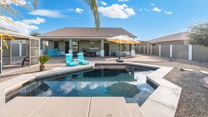 Um quintal com piscina, móveis de exterior e um espaço coberto de varanda.