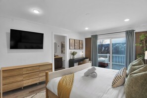 A hotel room with a bed, a wooden dresser, a desk, a TV, and a balcony with a view. - Luxury Camelback House: 5 bed: Hot Tub, Game Room, Mini-golf, Ski views (Tannersville)