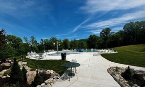 A pool area with lounge chairs, a table, and a well-maintained lawn. - Luxury Camelback House: 5 bed: Hot Tub, Game Room, Mini-golf, Ski views (Tannersville)