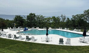 Une piscine rectangulaire avec une plage blanche, entourée de chaises longues et de parasols.