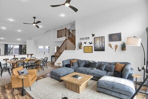 A spacious living area with a large sectional sofa, a wooden coffee table, and a dining area with a wooden table and chairs. - Luxury Camelback Summit: 5bed 4bath, Hot Tub, Game Room, Movie Room, Slope Views (Tannersville)