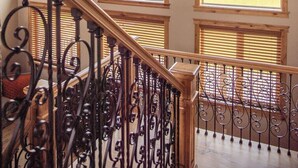 A staircase with wrought iron railings leading to a landing with large windows overlooking a field. - Teton View Retreat- Hot Tub - Game Room - Fire Pit (Alta)