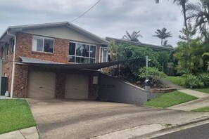 A two-story house with a garage, a covered driveway, and a small garden with palm trees. - Quaint studio with AC in friendly Kuluin neighborhood (Kuluin)