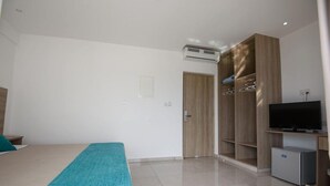 A modern hotel room with a bed, a TV, a wardrobe, and an air conditioning unit. - Annex Apartments (Ayia Napa)