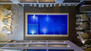 A rooftop pool with a blue water feature, surrounded by lounge chairs and umbrellas. - Annex Apartments (Ayia Napa)