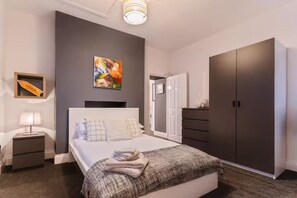 A modern bedroom with a large bed, a wardrobe, a nightstand, and a painting on the wall. - Cosy 1-bedroom apartment in Newport perfect for relaxing stays (Newport)